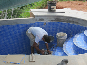 hand tiling a swimming pool